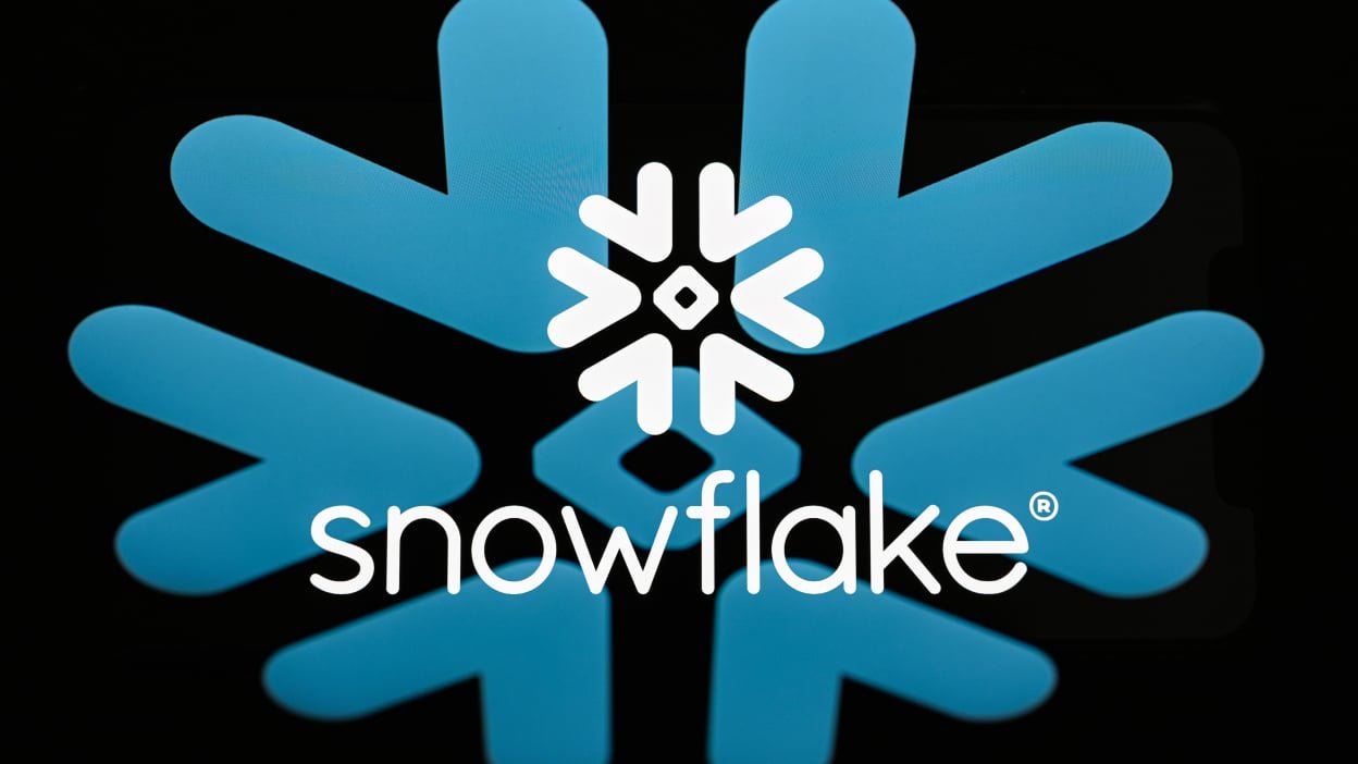 The Snowflake logo is displayed on a computer screen photographed using a double-exposure technique