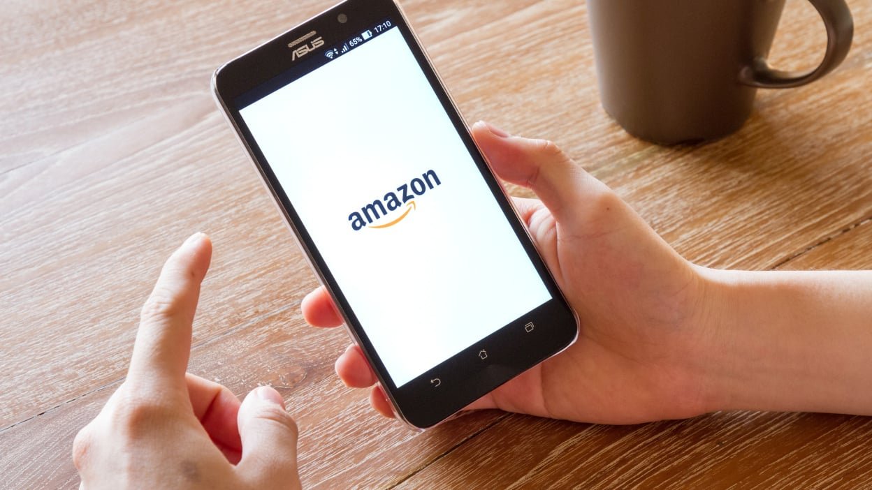Man hand holding screen shot of Amazon application showing on Asus Zenfone 2 mobile phone. Amazon is an American international electronic commerce company.